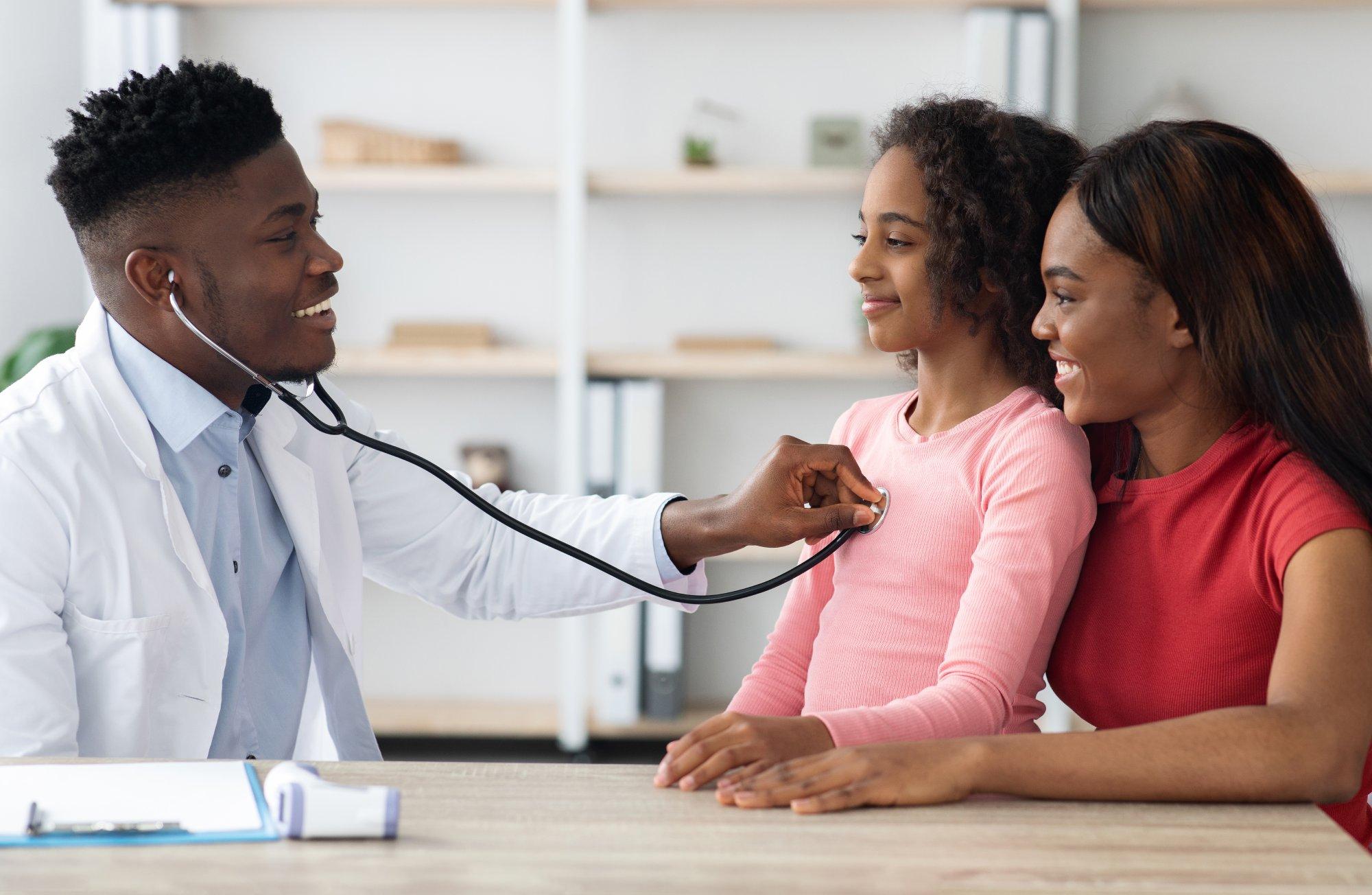 Black mother and daughter having checkup at pediatrician