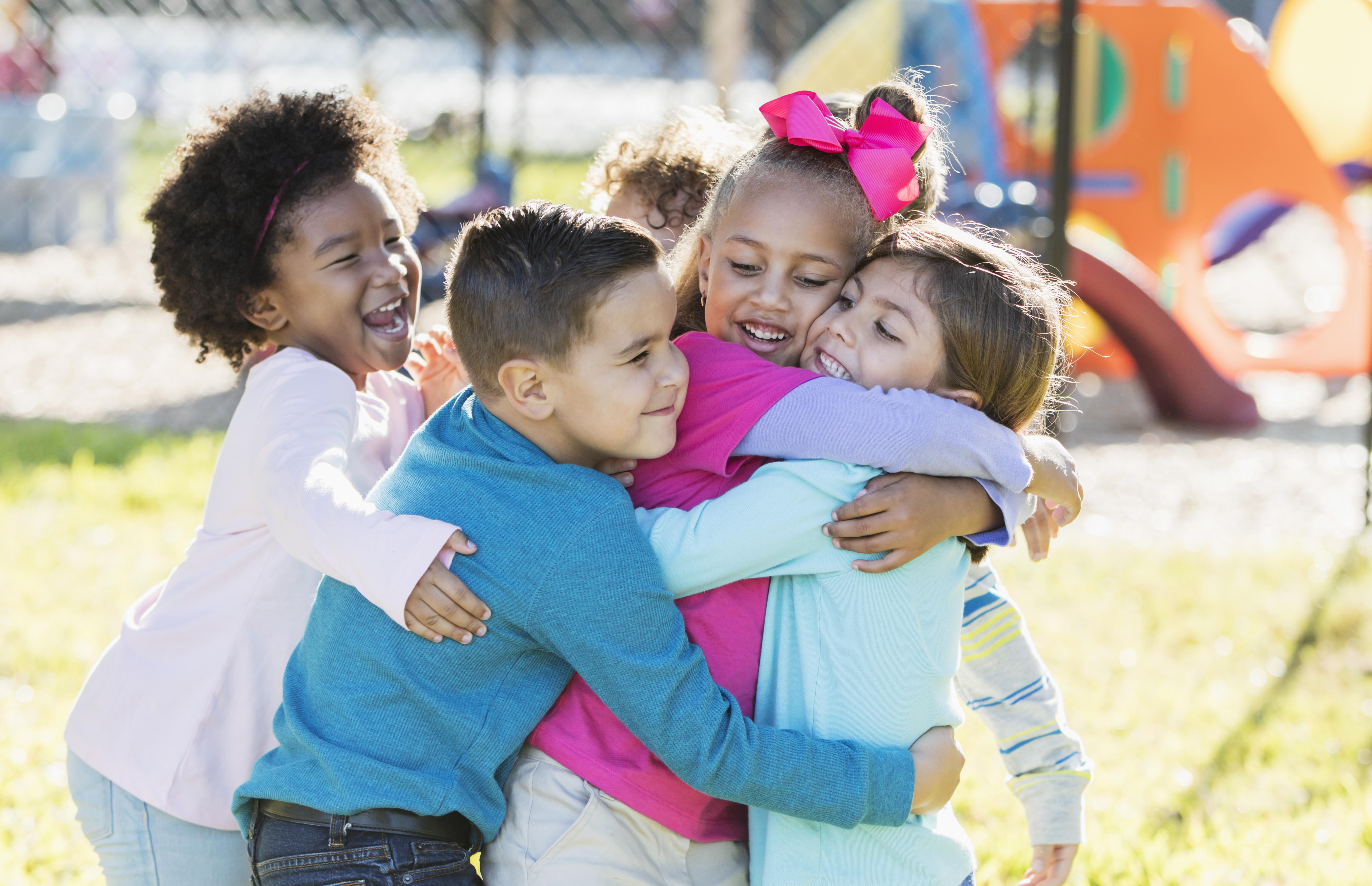 Children playing outdoors on playground, hugging