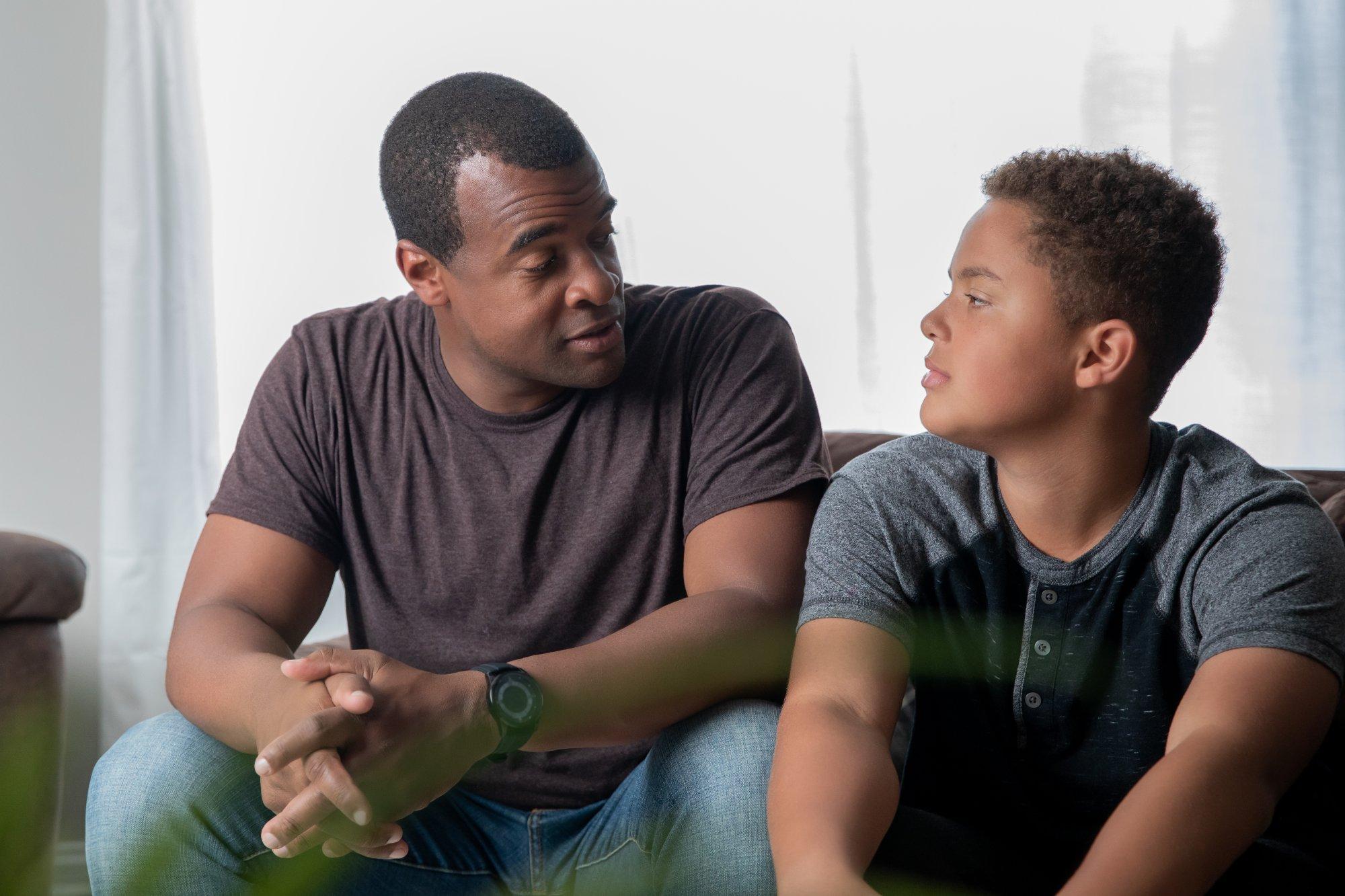 Father gives life advice to his young teenage son at home