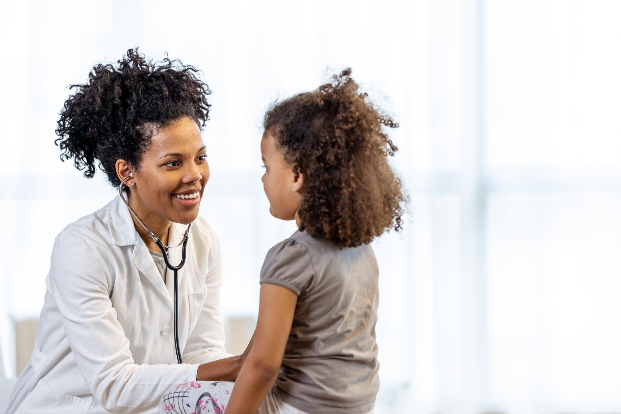 Female doctor checks girl's heartbeat