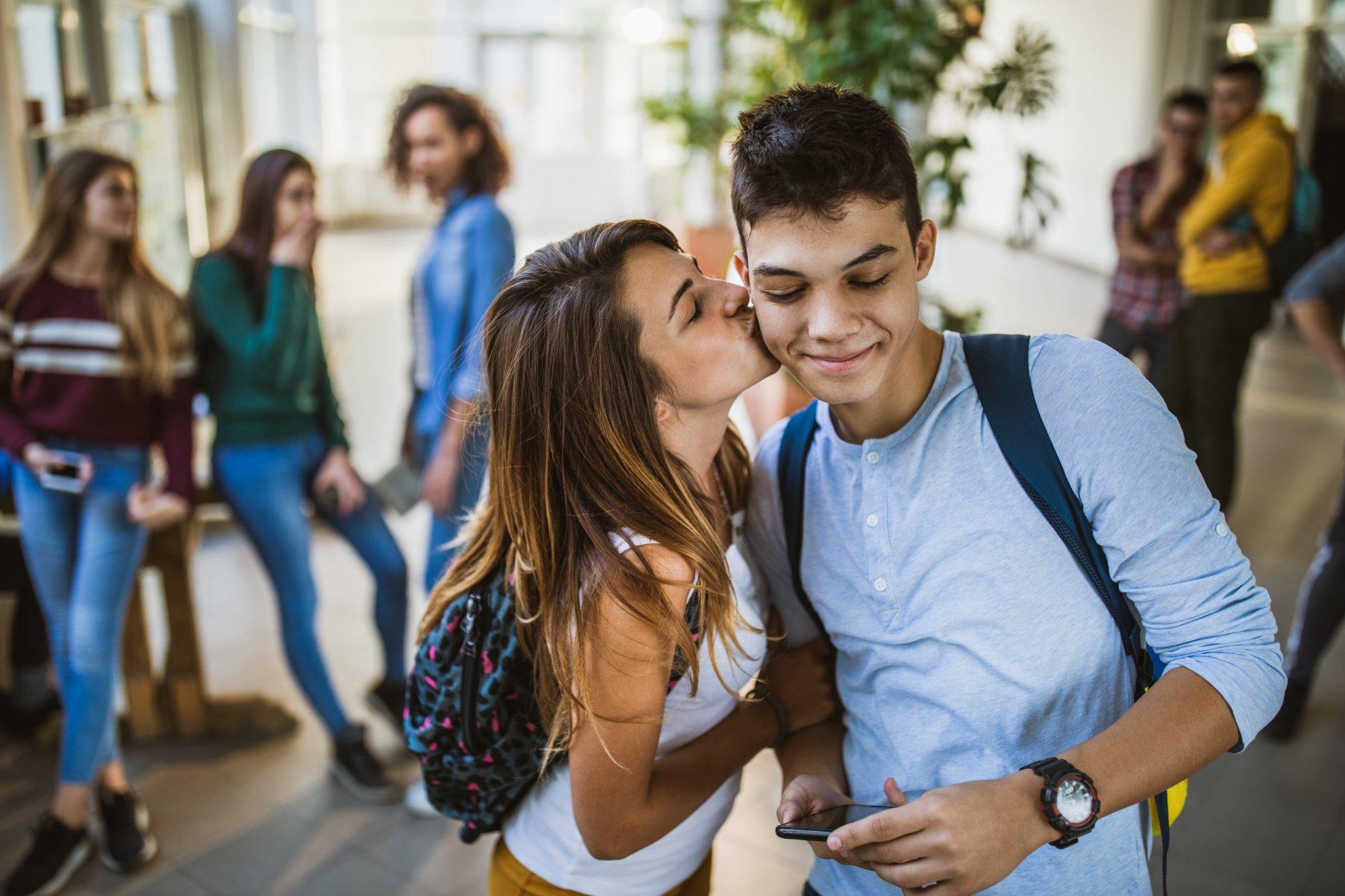 Female student kissing her boyfriend in a school hallway