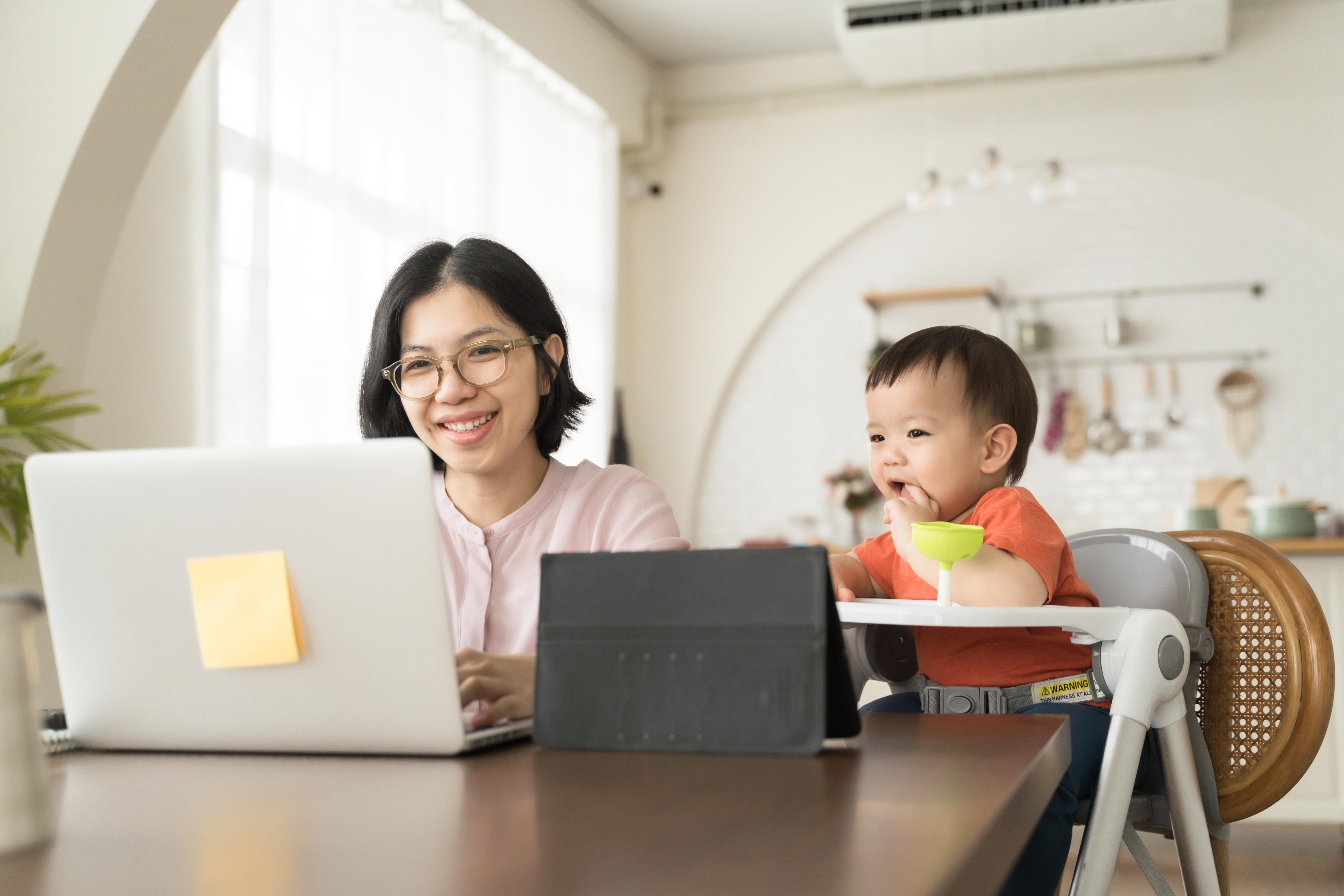 Happy smiling Asian Young mother and little son using laptop. Mom works from home office