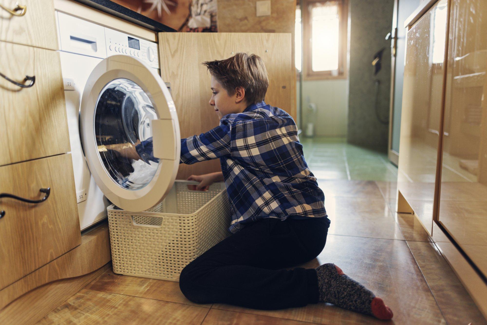 Little boy unloading a washing machine