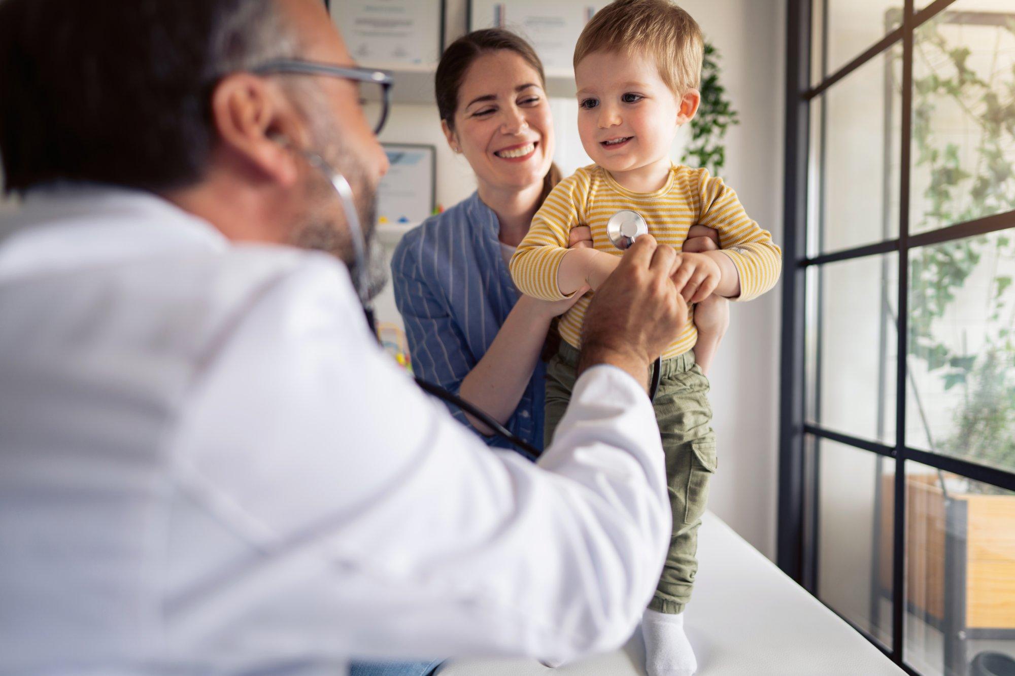 Mature male pediatrician examining little baby with a stethoscope