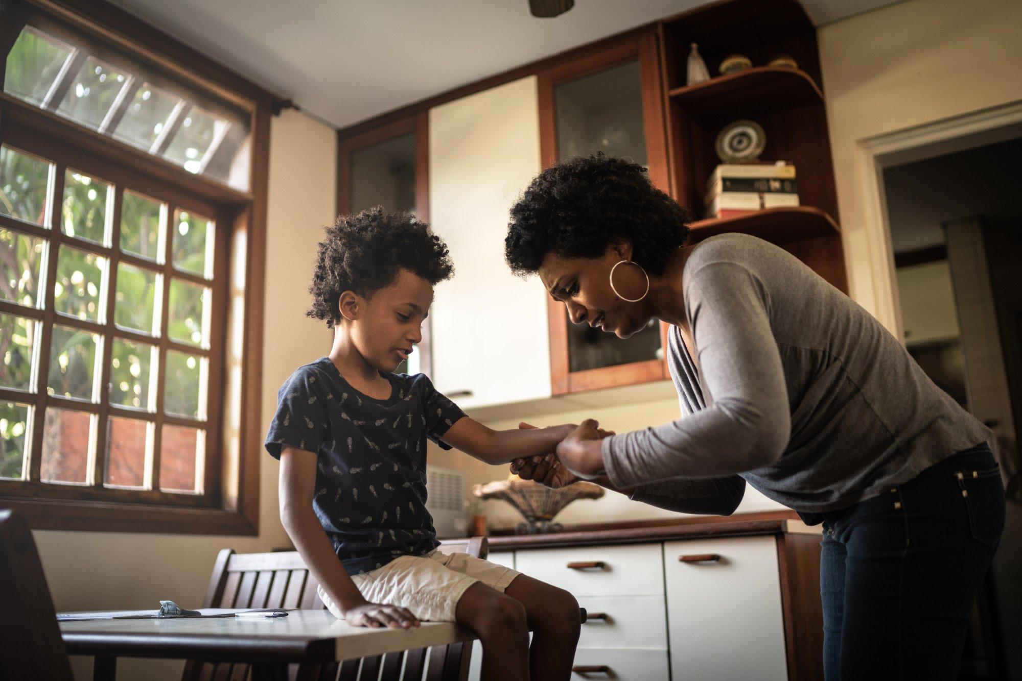 Mother applying adhesive bandage to son