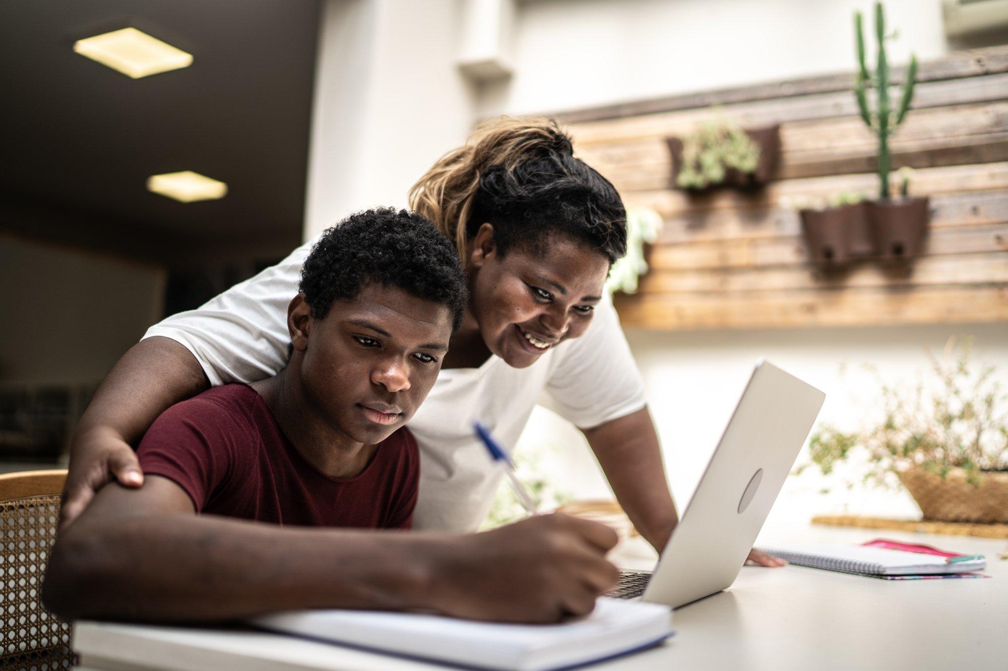 Mother helping teenager son on homeschooling