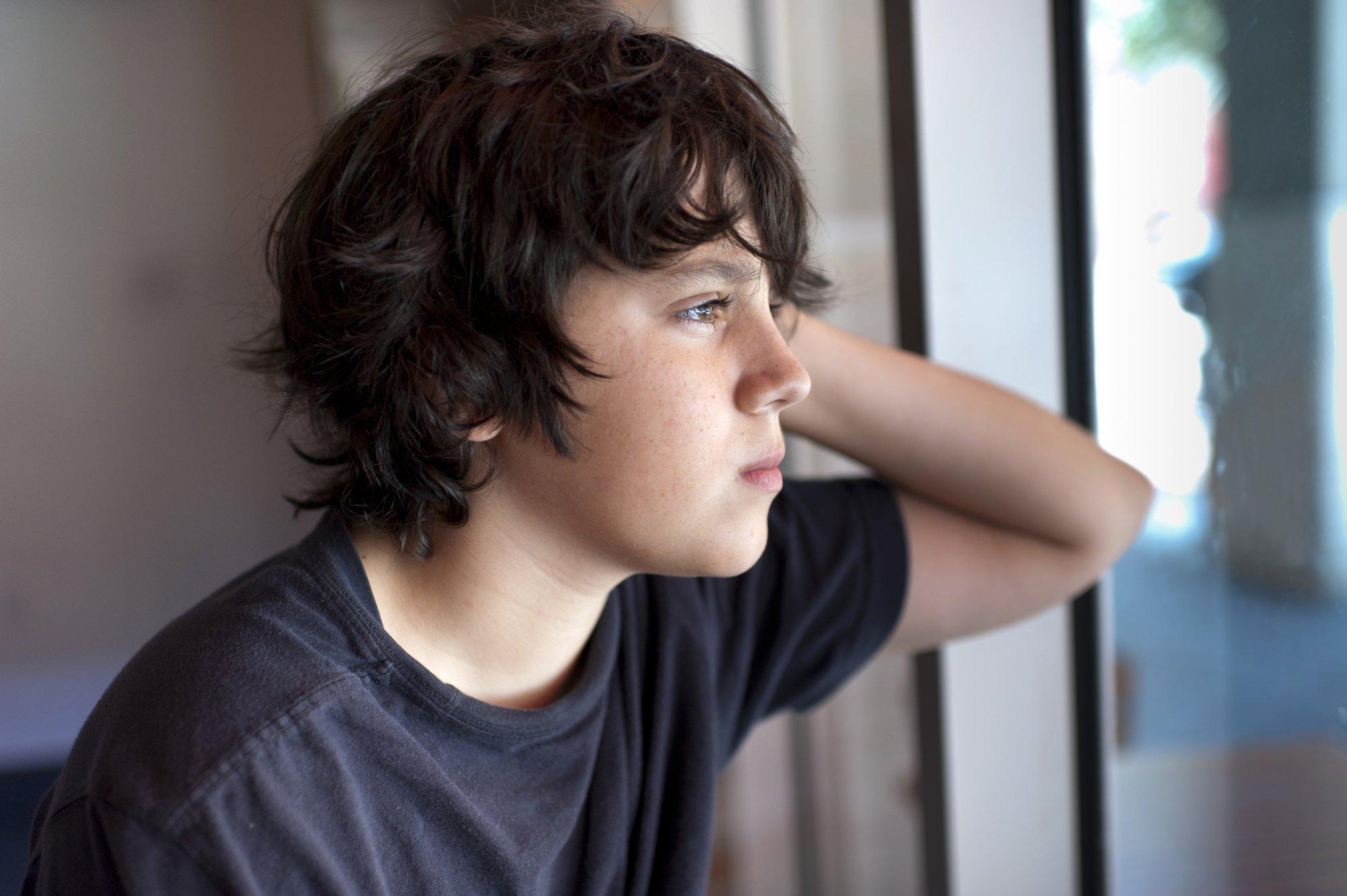 Pensive child looking through a window