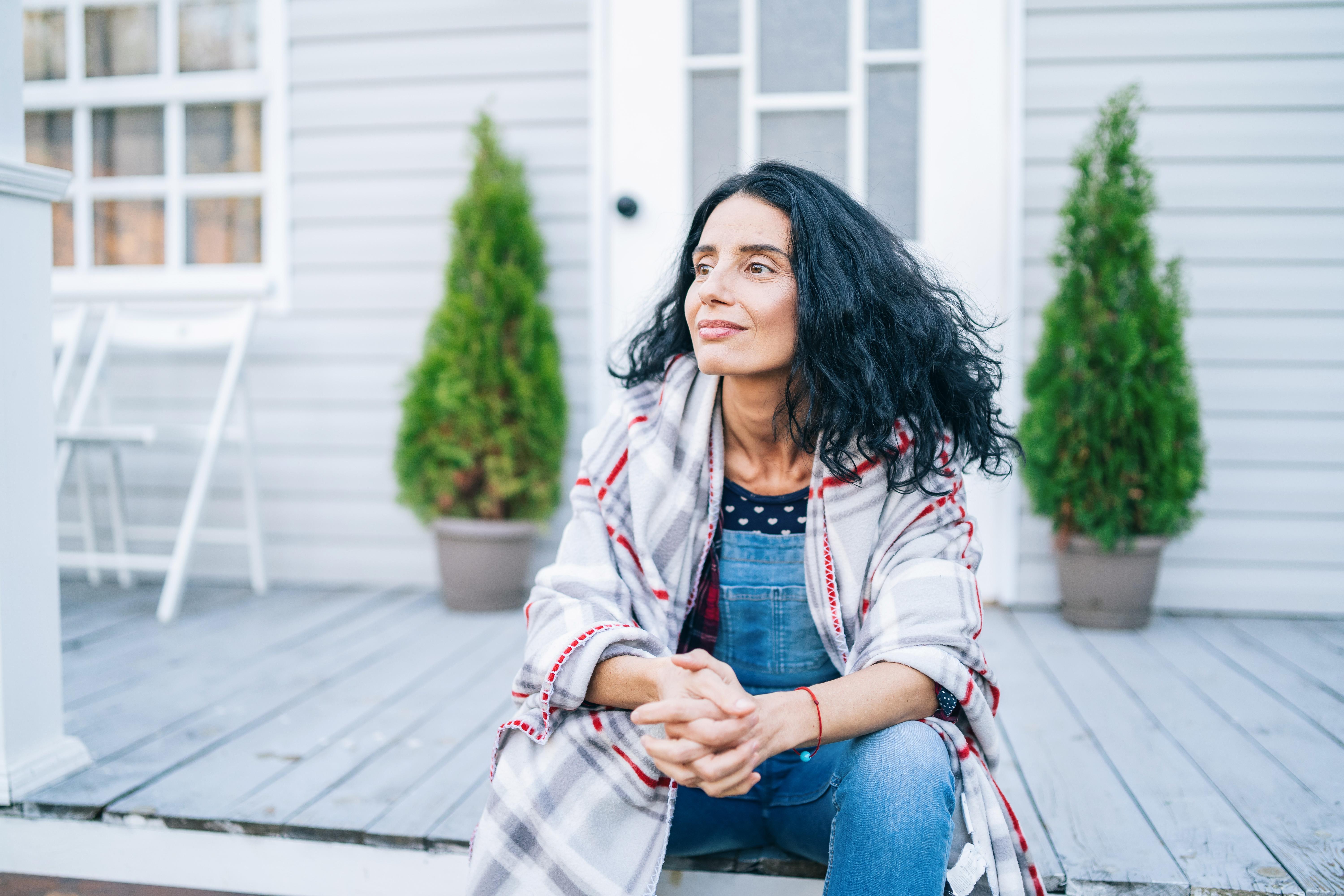 Sad mid adult woman sitting on stairs in front of her house