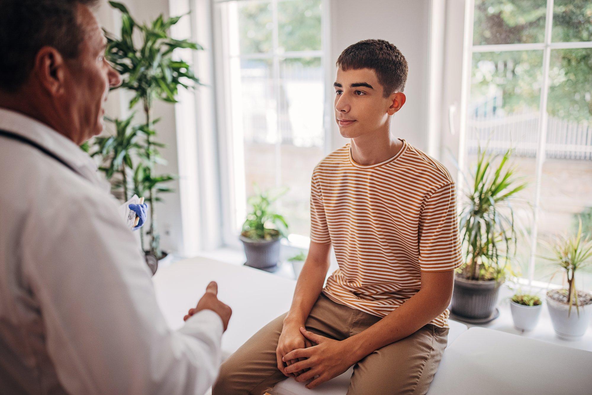 Senior doctor is talking to teenage patient in the medical examination room