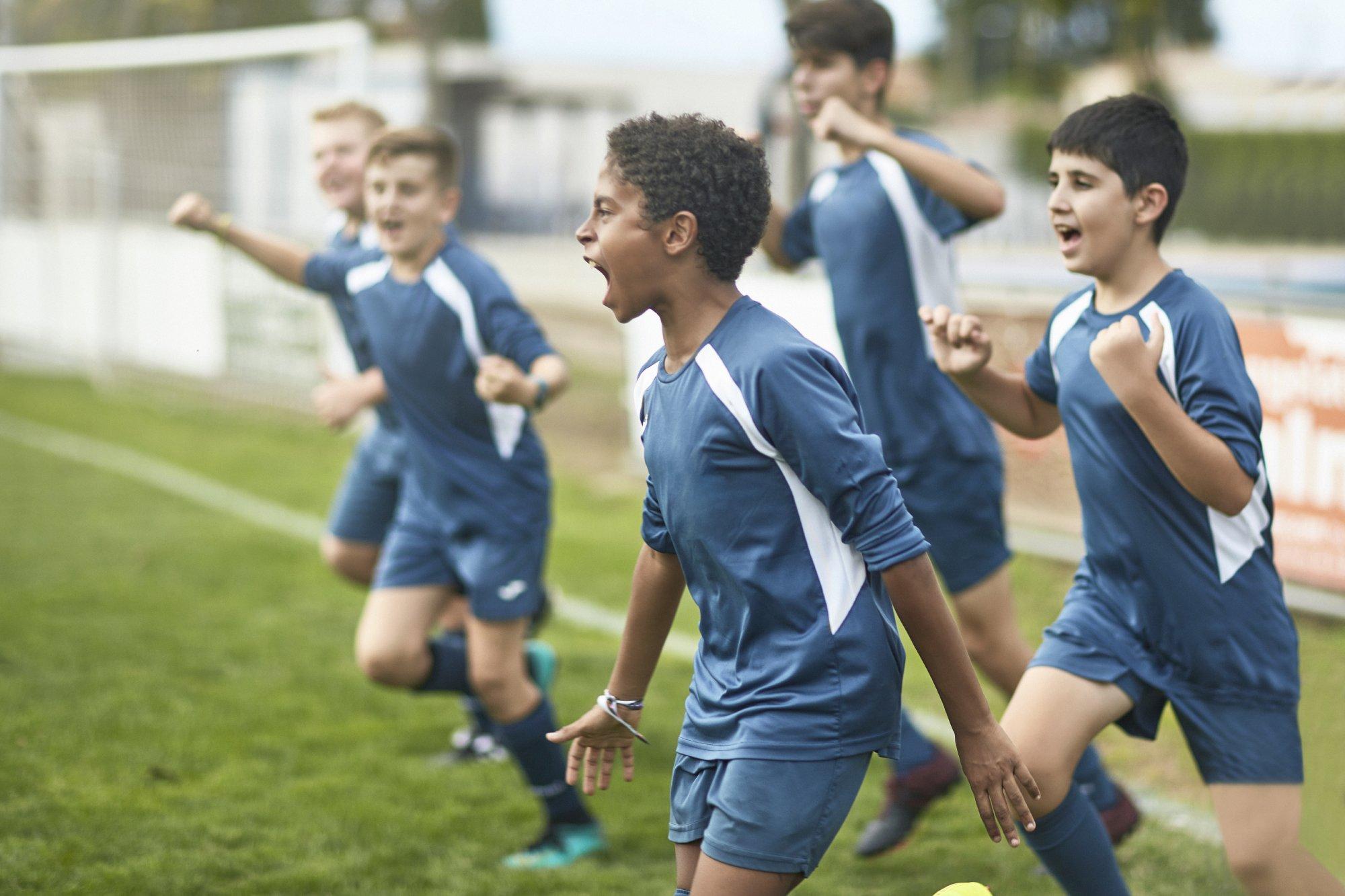 Team of Confident Young Male Footballers Running Onto Field